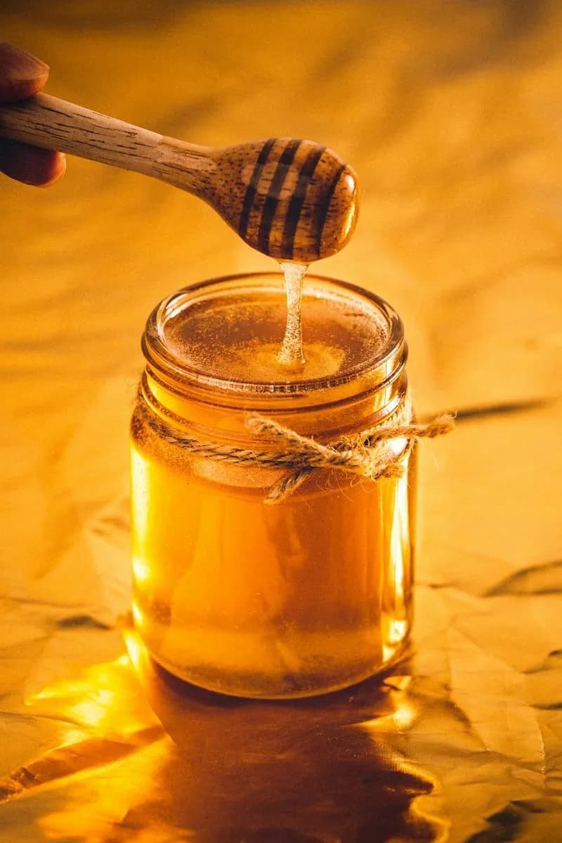 Honey dripping from a dipper into a jar