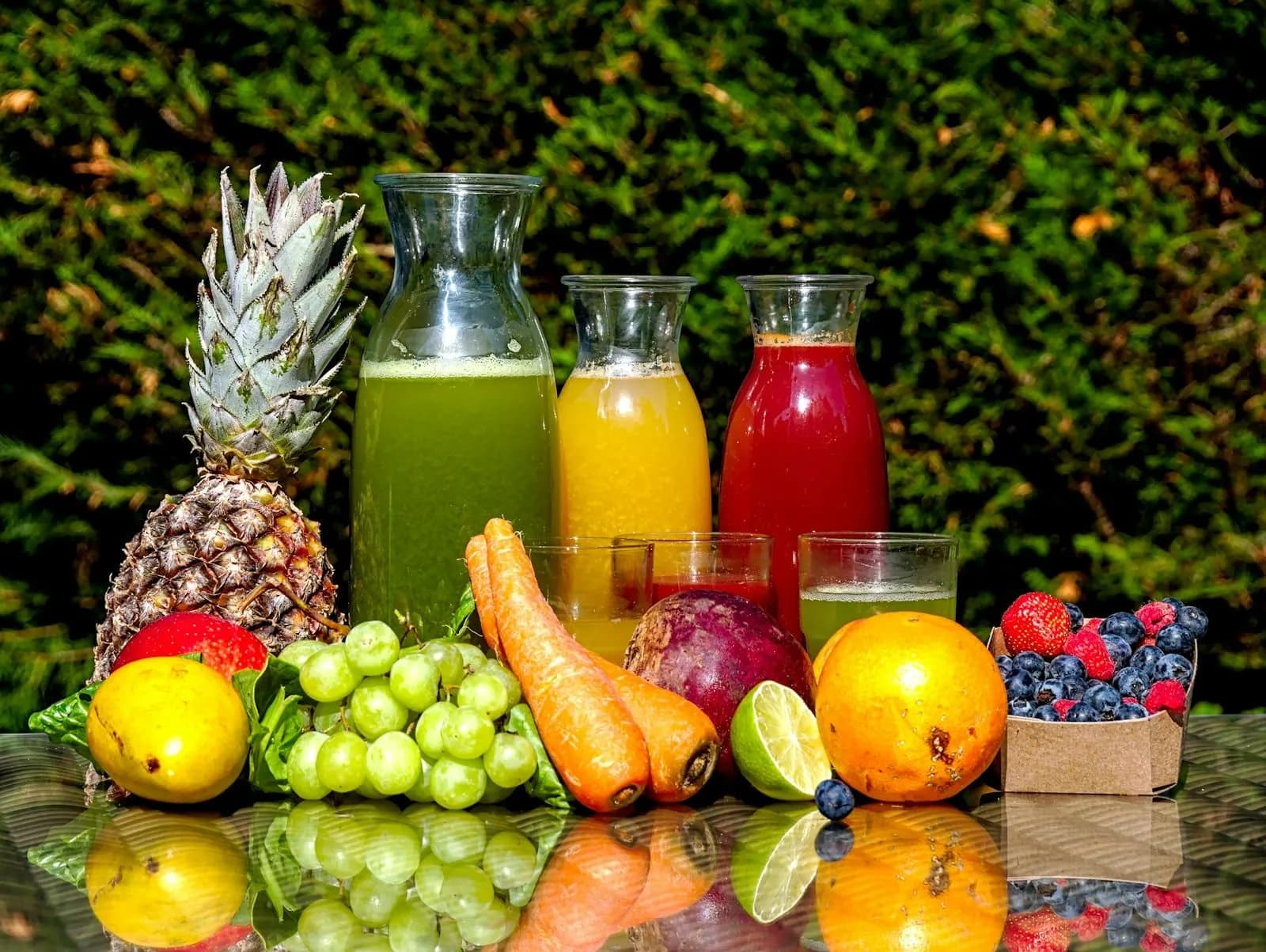Carafes of green, orange and red juice among fresh fruit