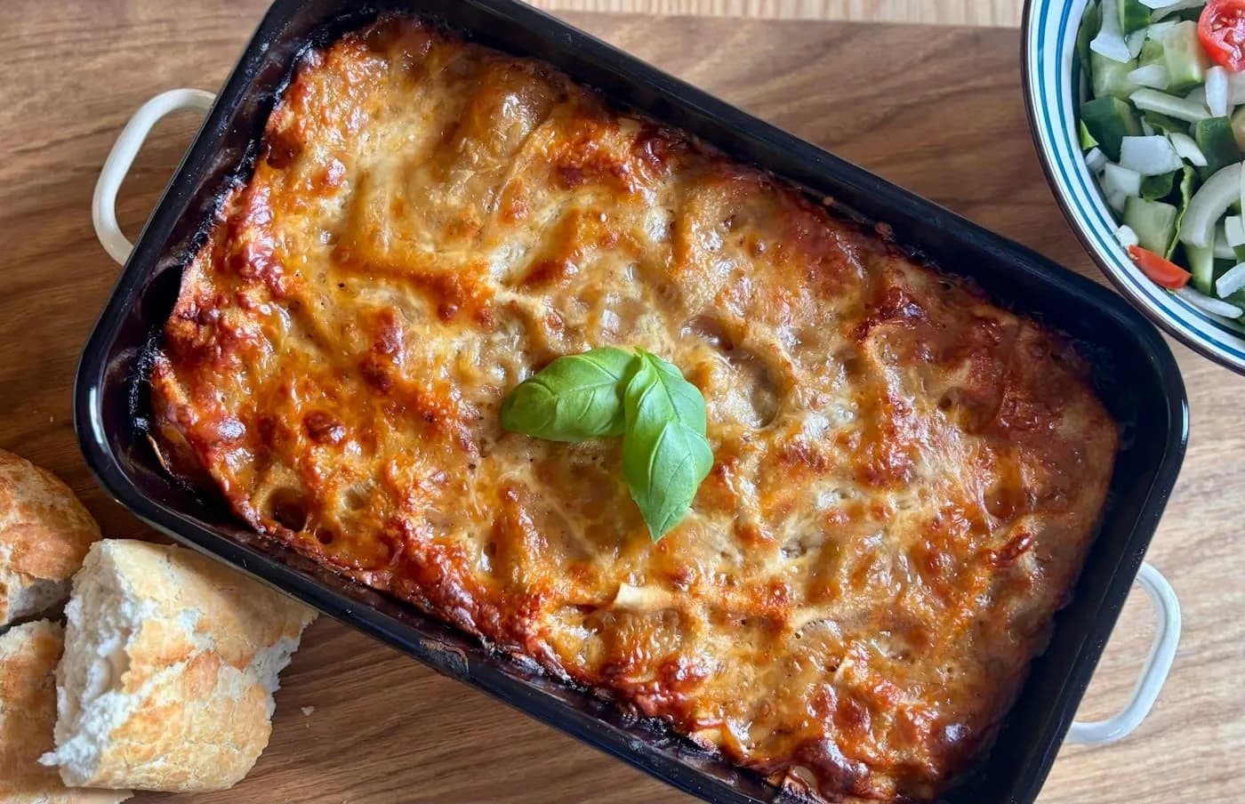 A tray of baked lasagne topped with basil