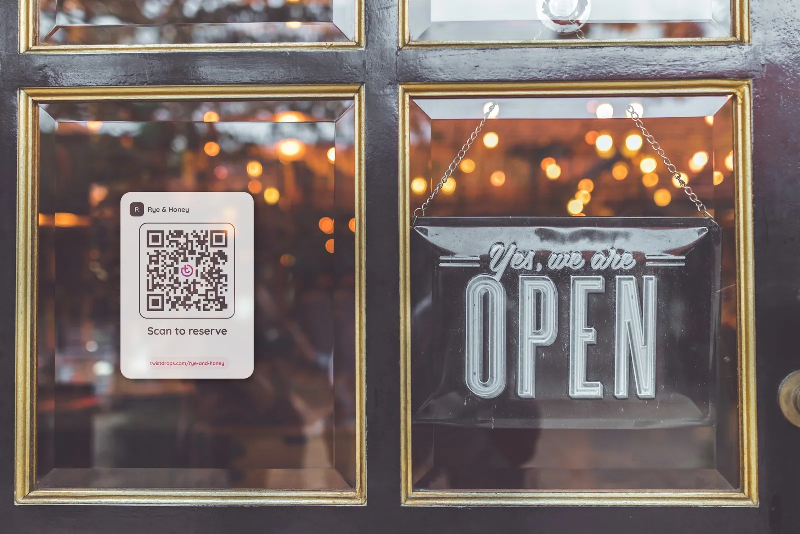 A QR code sticker on a shop’s glass door, beside an open sign